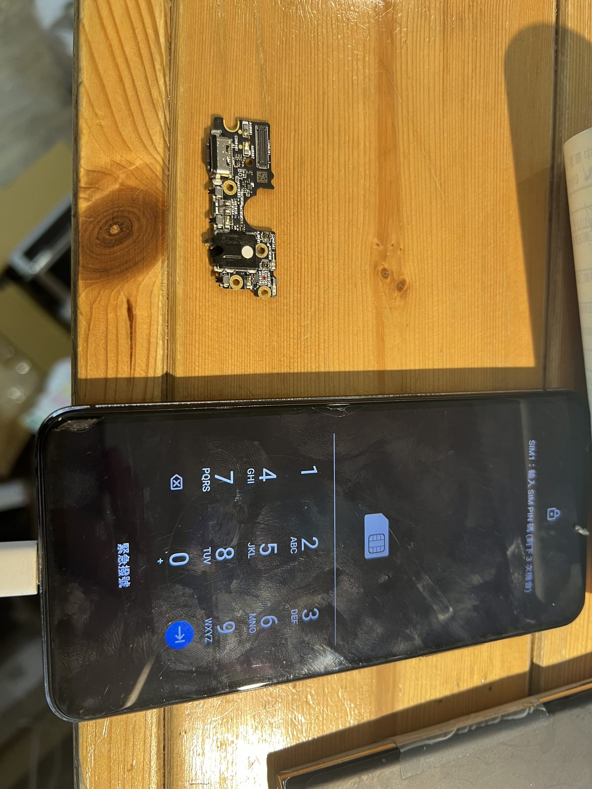 ASUS ZenFone 5Z 拆下的充電埠小板，以及維修完成後可正常開機的手機